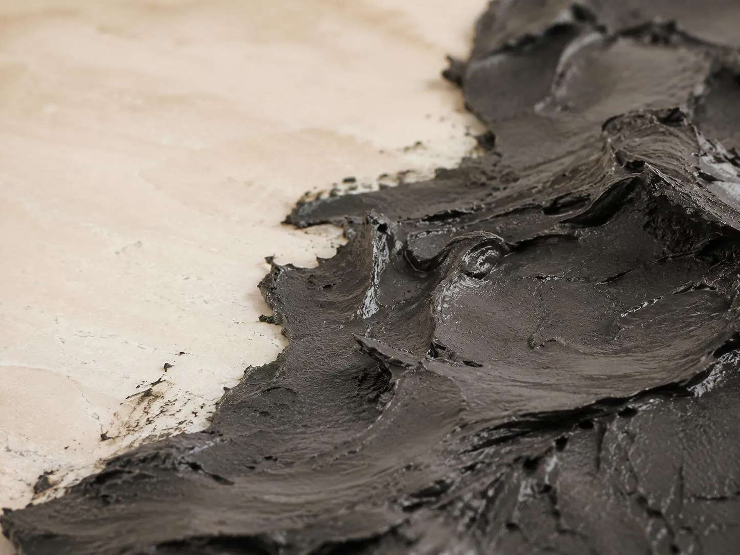 Black Dead Sea mineral mud spread across a pale stone surface